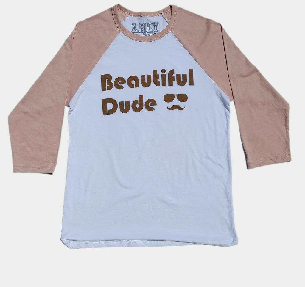 3/4 sleeve length raglan t-shirt with peach arms and white body. Decorated with the phrase beautiful dude followed by aviator glasses and mustache silhouette